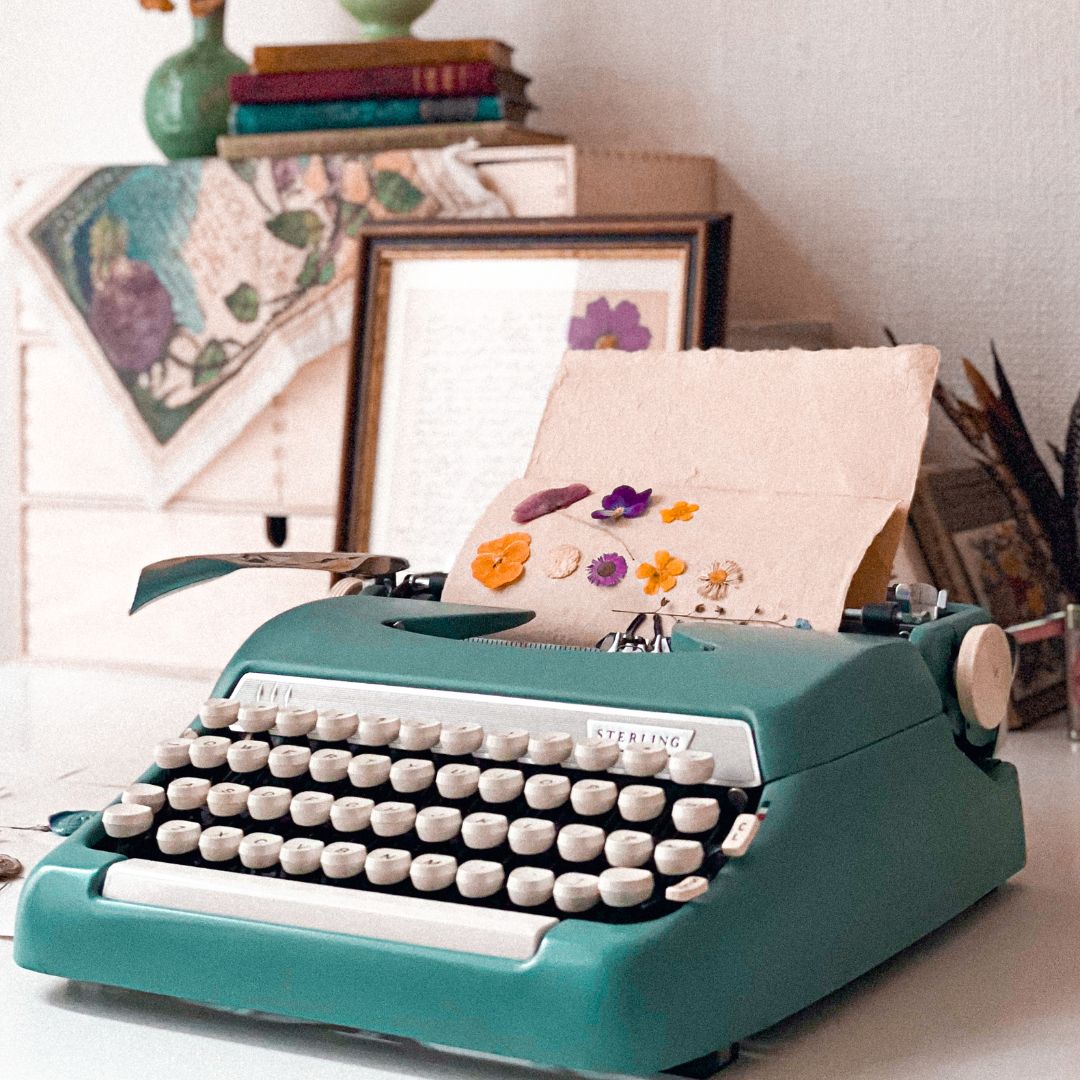 machine à écrire bleu avec des fleurs séchées - site eco-conçu - communication plus durable